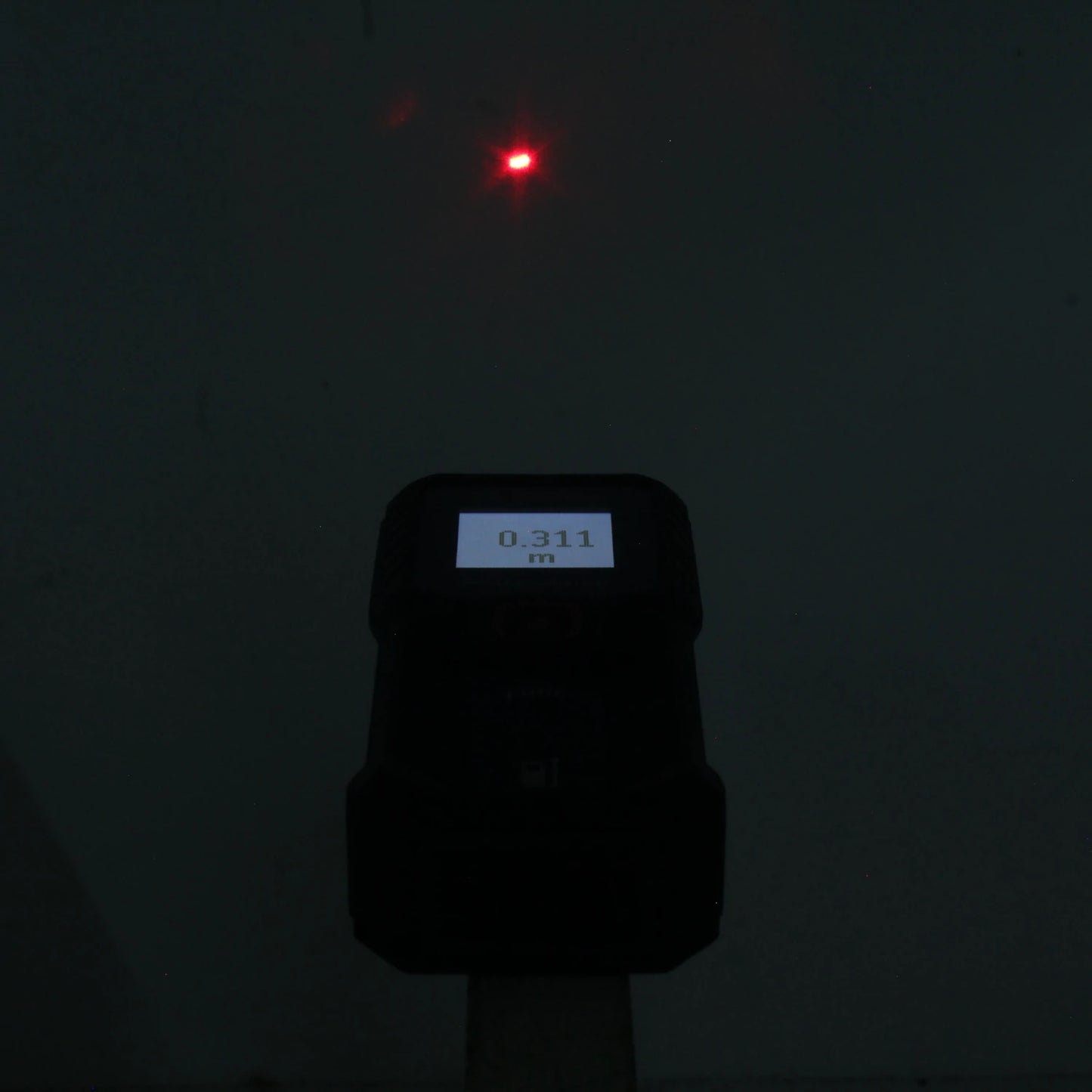 Medidor láser Bosch de distancia con punto rojo y pantalla digital mostrando 0.311 m.