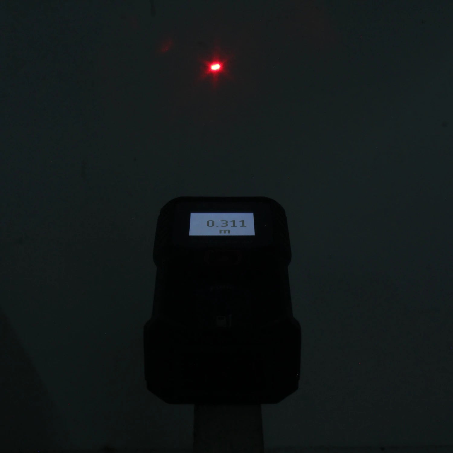 Medidor láser Bosch de distancia con punto rojo y pantalla digital mostrando 0.311 m.