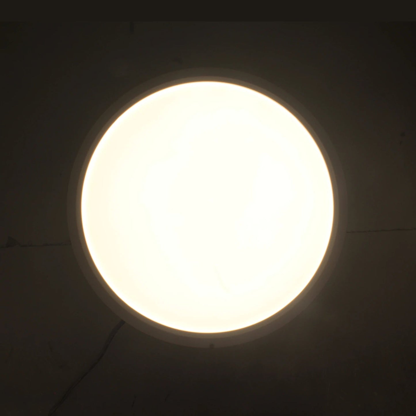 Lámpara panel LED redonda de sobreponer con luz blanca cálida encendida, ideal para techo