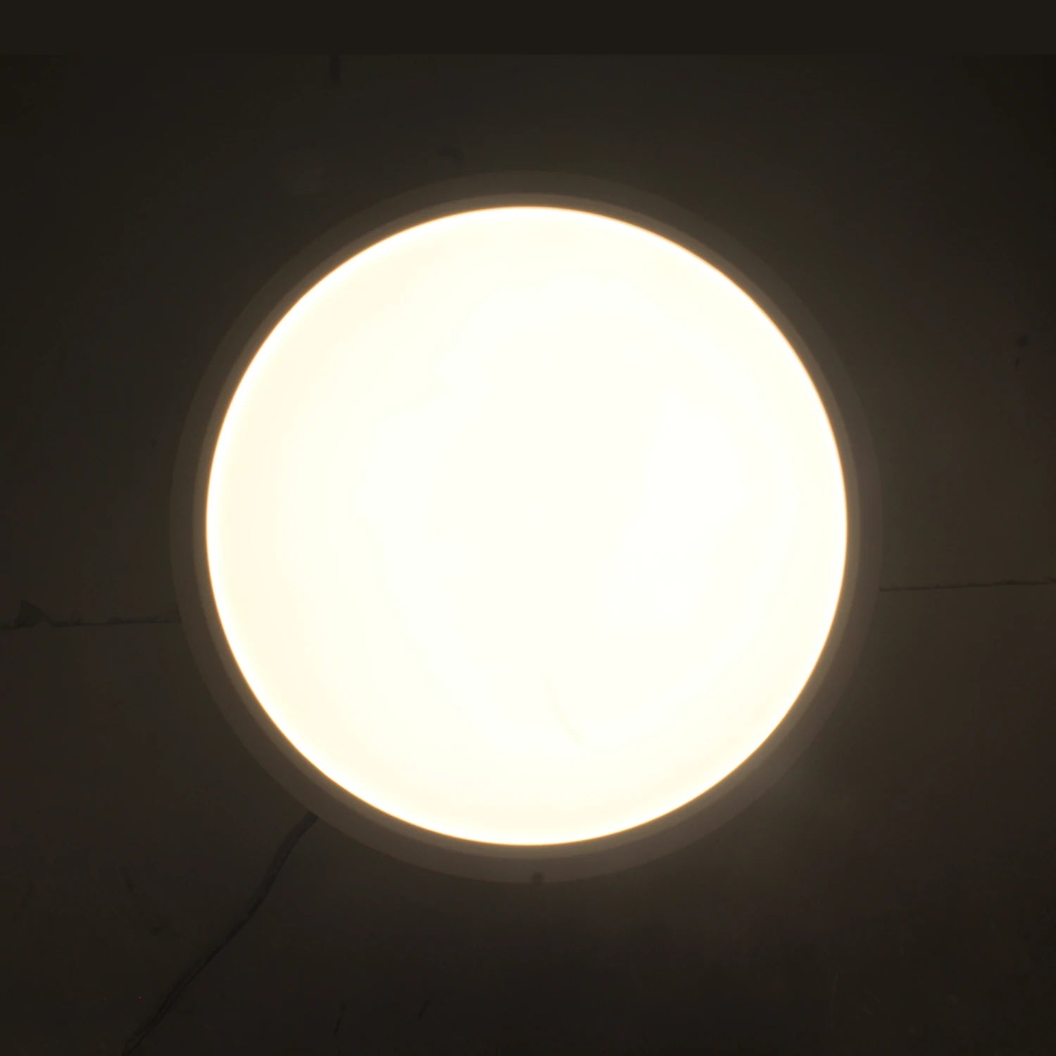 Lámpara panel LED redonda de sobreponer con luz blanca cálida encendida, ideal para techo